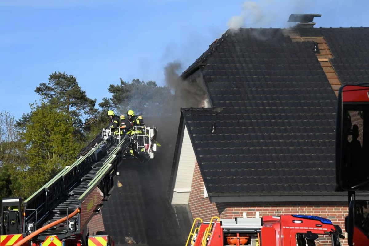 Feuerwehrleute bekämpfen über die Drehleiter einen Dachstuhlbrand an einem Einfamilienhaus